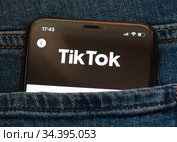 Логотип TikTok ("ТикТок") на экране мобильного телефона, лежащего в кармане джинсов. Крупный план (2020 год). Редакционное фото, фотограф E. O. / Фотобанк Лори