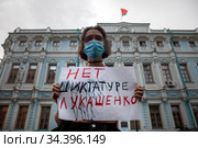 Девушка держит плакат с надписью "Нет диктатуре Лукашенко" на фоне здания посольства Республики Беларусь в Москве, Россия (2020 год). Редакционное фото, фотограф Николай Винокуров / Фотобанк Лори