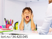Screaming autistic boy close ears during lesson. Стоковое фото, фотограф Сергей Новиков / Фотобанк Лори