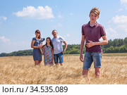Handsome boy full length portrait with his father and preteen sister on background, Caucasian family in wheat field. Стоковое фото, фотограф Кекяляйнен Андрей / Фотобанк Лори