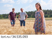 Pretty girl in summer light dress portrait with her father and preteen brother on background, Caucasian family in wheat fields. Стоковое фото, фотограф Кекяляйнен Андрей / Фотобанк Лори