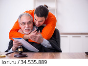 Old male judge meeting with young captive in courthouse. Стоковое фото, фотограф Elnur / Фотобанк Лори