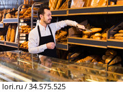 Baker puts baguettes and bread on the counter. Стоковое фото, фотограф Яков Филимонов / Фотобанк Лори