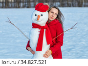 Блондинка в красном пальто обнимает снеговика. Стоковое фото, фотограф 1Andrey Милкин / Фотобанк Лори
