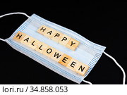 Medical mask and wooden words Happy Halloween on black. Halloween background decor holiday concept. Стоковое фото, фотограф Papoyan Irina / Фотобанк Лори
