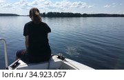 Teenager girl sits on bow of fast moving motorboat, speedboat floating on lake water surface, copyspace. Стоковое видео, видеограф Кекяляйнен Андрей / Фотобанк Лори