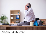 Old male employee suffering from radiculitis at workplace. Стоковое фото, фотограф Elnur / Фотобанк Лори