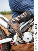 Rider with motocross boot standing on dirt motorcycle, foot is on kick starter. Close up view at safety apparel. Стоковое фото, фотограф Кекяляйнен Андрей / Фотобанк Лори