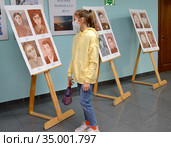 Девочка-подросток рассматривает детские рисунки на выставке  в период эпидемии коронавируса COVID-19. Калининград (2020 год). Редакционное фото, фотограф Ирина Борсученко / Фотобанк Лори