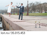 Newlywed couple walking on embarkment, two stem glasses with champagne standing on granite. Стоковое фото, фотограф Кекяляйнен Андрей / Фотобанк Лори