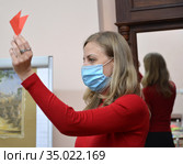 Учитель показывает бумажную деталь самоделки-оригами из цветной бумаги. Детский мастер-класс в период эпидемии коронавируса COVID-19 в России. Стоковое фото, фотограф Ирина Борсученко / Фотобанк Лори