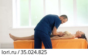 Positive male osteopath treating belly of patient. Стоковое видео, видеограф Гурьянов Андрей / Фотобанк Лори