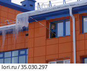 Мужчина сбивает палкой сосульки (2020 год). Редакционное фото, фотограф Максим Гулячик / Фотобанк Лори