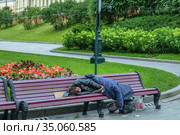 Москва, Александровский Сад, бездомный человек спит на лавочке летним утром (2020 год). Редакционное фото, фотограф glokaya_kuzdra / Фотобанк Лори