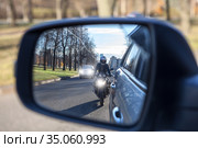 Mutual passing, motorcycle and vehicle with dazzle lighting overtaking the car, view in a side mirror. Improper driving or traffic violation. Стоковое фото, фотограф Кекяляйнен Андрей / Фотобанк Лори