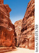 Tourists in narrow passage of rocks of Petra canyon in Jordan. Petra has been a UNESCO World Heritage Site since 1985. Way through Siq gorge to stone city Petra (2012 год). Стоковое фото, фотограф Наталья Волкова / Фотобанк Лори