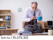 Old male employee suffering from radiculitis at workplace. Стоковое фото, фотограф Elnur / Фотобанк Лори