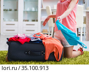 Woman trying to fit all clothing to suitacase before vacation. Стоковое фото, фотограф Elnur / Фотобанк Лори