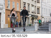Trendy fashinable teenagers riding public rental electric scooters in urban city environment. New eco-friendly modern public city transport in Ljubljana, Slovenia. Стоковое фото, фотограф Matej Kastelic / Фотобанк Лори