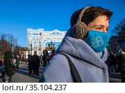 Люди носят защитные маски во время резкого похолодания в городе Москве на фоне новогодних инсталляций на Пушкинской площади в центре города, Россия (2020 год). Редакционное фото, фотограф Николай Винокуров / Фотобанк Лори