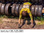 Russia, Samara, June 2019: athletic youth participates in a race of heroes and overcomes obstacles car tires on a summer day in the village of Roshchinsky . Text in Russian: race of heroes, platoon. Редакционное фото, фотограф Акиньшин Владимир / Фотобанк Лори