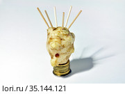 Coronavirus symbol of jerusalem artichoke and toothpicks on a pedestal of coins, on a white background. Стоковое фото, фотограф Владимир Литвинов / Фотобанк Лори