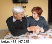 A man and an older woman sit at a table and hold on to the phone. Стоковое фото, фотограф Владимир Ушаров / Фотобанк Лори