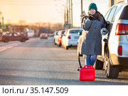 Attractive woman with empty gas tank standing on roadside with red plastic canister, copy space. Стоковое фото, фотограф Кекяляйнен Андрей / Фотобанк Лори