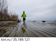 Ребенок в зеленой куртке бежит по морской литорали (2020 год). Редакционное фото, фотограф Яковлев Сергей / Фотобанк Лори