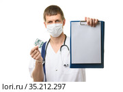 Врач показывает в кадр планшетку с белым листом бумаги, в другой руке держит лекарства. Стоковое фото, фотограф Иванов Алексей / Фотобанк Лори