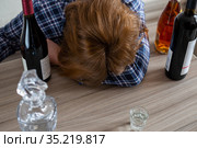 woman surrounded by bottles of alcohol - concept of female alcoholism. Стоковое фото, фотограф Володина Ольга / Фотобанк Лори