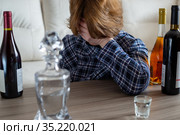 Drunk woman sitting at table with bottles of wine. Стоковое фото, фотограф Володина Ольга / Фотобанк Лори