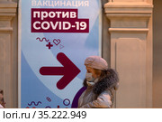 Женщина стоит в очереди в мобильный пункт вакцинации от новой коронавирусной инфекции COVID-19 вакциной Спутник V в ГУМе города Москвы, Россия (2021 год). Редакционное фото, фотограф Николай Винокуров / Фотобанк Лори
