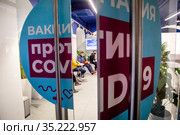 Люди сидят в очереди в мобильный пункт вакцинации от новой коронавирусной инфекции COVID-19 вакциной Спутник V в ГУМе города Москвы, Россия (2021 год). Редакционное фото, фотограф Николай Винокуров / Фотобанк Лори