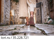 Detail shot of female legs wearing comfortable travel sandals walking on old medieval cobblestones street dring sightseeing city tour. Travel, tourism and adventure concept. Стоковое фото, фотограф Matej Kastelic / Фотобанк Лори