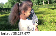Caucasian teen age girl carrying her toddler sister on hands while walking in green plant labyrinth. Стоковое видео, видеограф Кекяляйнен Андрей / Фотобанк Лори