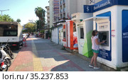 The largest Turkish Bankamatik network for withdraw cash. Group of ATM of different banks stand on the street for vacationers. Woman in mask uses atm. Alanya, Turkey (2021 год). Редакционное видео, видеограф Кекяляйнен Андрей / Фотобанк Лори