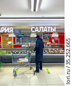 Покупатель с тележкой в отделе кулинарии в супермаркете (2021 год). Редакционное фото, фотограф Мария Кылосова / Фотобанк Лори