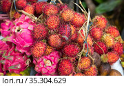 Красные фрукты драгон фрут (dragon fruit) и рамбутана лежат на прилавке. Индонезия. (2018 год). Стоковое фото, фотограф Галина Савина / Фотобанк Лори