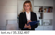 Young adult female assistant standing with clipboard and making notes in modern office. Стоковое видео, видеограф Яков Филимонов / Фотобанк Лори