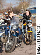 Two Caucasian women motorcyclists talk incessantly while sitting face-to-face on their motorcycles, spring season. Стоковое фото, фотограф Кекяляйнен Андрей / Фотобанк Лори