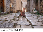 Detail shot of female legs wearing comfortable travel sandals walking on old medieval cobblestones street dring sightseeing city tour. Travel, tourism and adventure concept. Стоковое фото, фотограф Matej Kastelic / Фотобанк Лори
