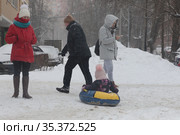 Мужчина везёт ребёнка на балоне по снегу (2021 год). Редакционное фото, фотограф Дмитрий Неумоин / Фотобанк Лори