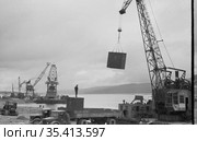 Перегрузка контейнеров с кузова грузового автомобиля на морское судно, погрузочные работы в гавани реки Лена, краны на плавучих платформах, Осетрово, Чукотка, 1963 год. Стоковое фото, фотограф Варфоломей Тетерин / Фотобанк Лори