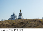 Ancient white stone Church of the Intercession of the Virgin (Shopino, Belgorod district, Russia). Beautiful landscape in pale colors, view of the temple on the hill, against the light blue sky. Стоковое фото, фотограф irisff / Фотобанк Лори