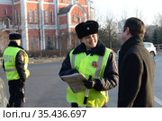Инспектор дорожно-патрульной службы полиции проверяет документы водителя остановленного автомобиля (2016 год). Редакционное фото, фотограф Free Wind / Фотобанк Лори
