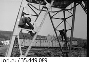 Несколько работников грузового порта занимается установка металлических опор для портального крана, создание инфраструктуры для грузовой Гавани, морское судно стоящее на суше позади них, Осетрово, Якутия, 1963 год. Стоковое фото, фотограф Варфоломей Тетерин / Фотобанк Лори