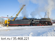 Загрузка углем старого советского паровоза ЛВ-0522 на железнодорожной станции мартовским днем. Сортавала, Карелия (2021 год). Редакционное фото, фотограф Виктор Карасев / Фотобанк Лори