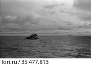 Небольшой моторный корабль плывёт по водам реки Лена, морское судно уплывает вдаль в сторону горизонта, облачное небо над водоемом, Осетрово, Якутия, 1963 год. Стоковое фото, фотограф Варфоломей Тетерин / Фотобанк Лори