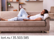 Young lazy man in oversleeping concept at home. Стоковое фото, фотограф Elnur / Фотобанк Лори